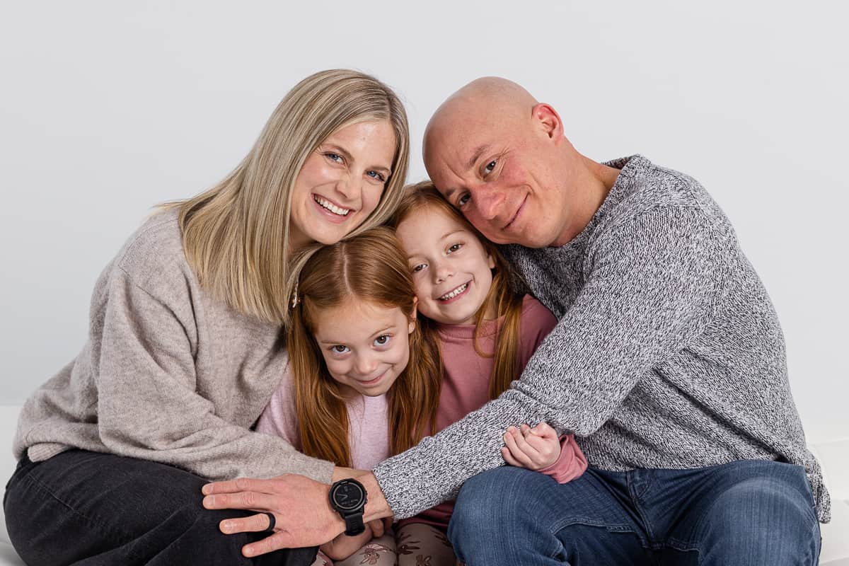 Family with two twin girl hugging in photo studio